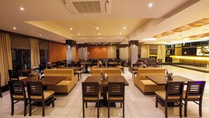 Un restaurante espacioso con varias zonas de comedor, que incluyen cabinas y mesas con sillas.