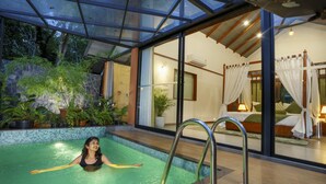 A swimming pool with a glass ceiling, surrounded by potted plants and a bed with a canopy. - Crystal Kuruva Nature Resort & Spa (Sulthan Bathery)