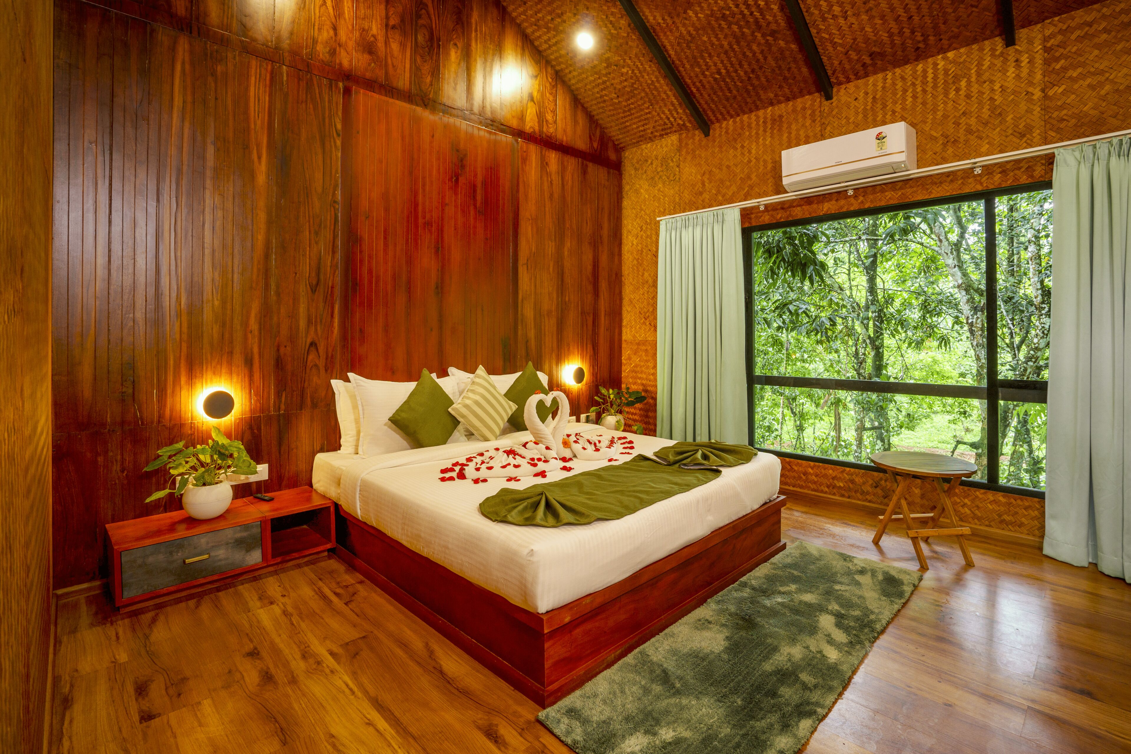 A wooden-themed bedroom with a bed, bedside tables, and a window with a view of greenery.