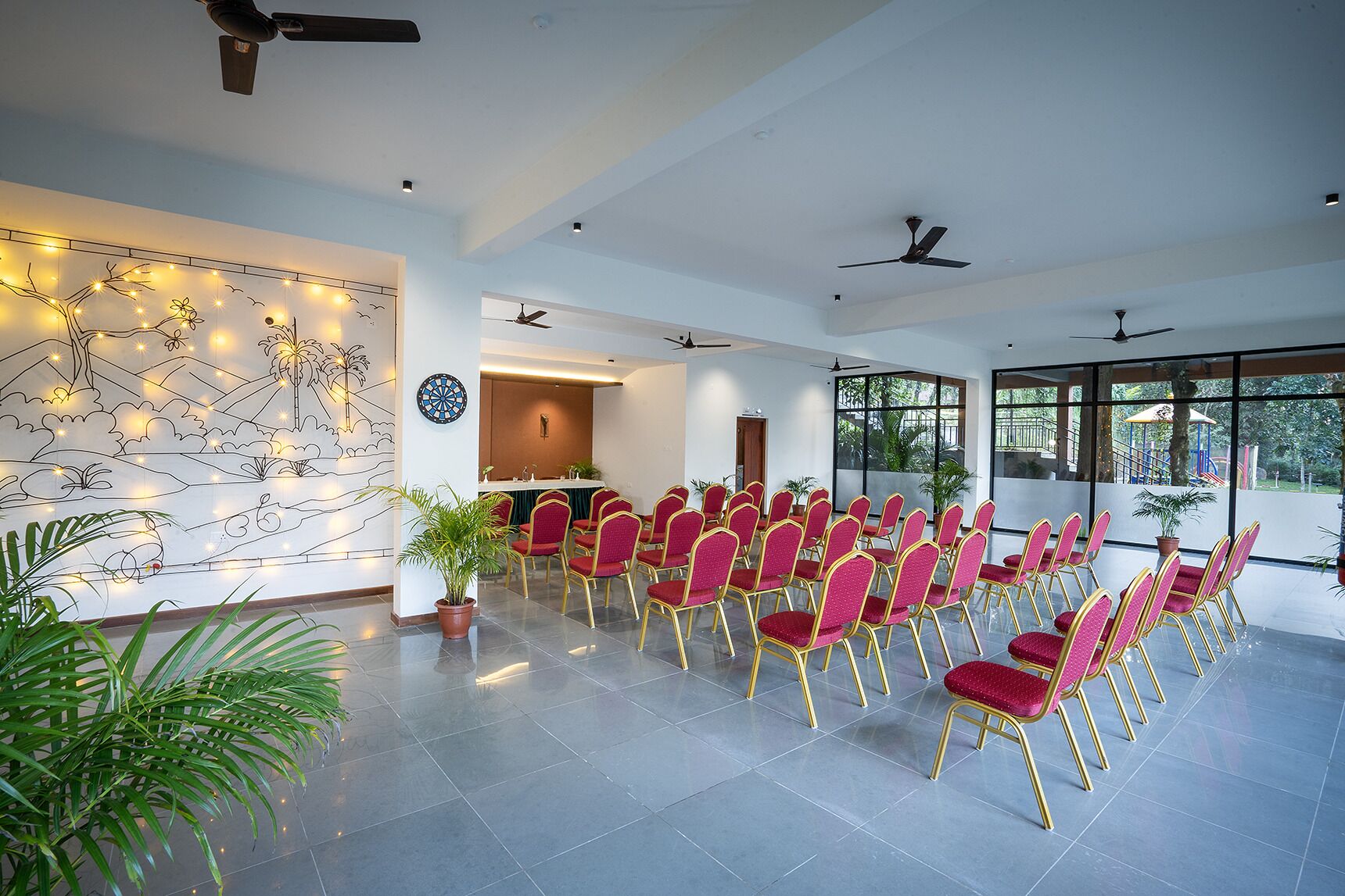 A conference room with rows of red chairs, a dartboard, and a mural on the wall.