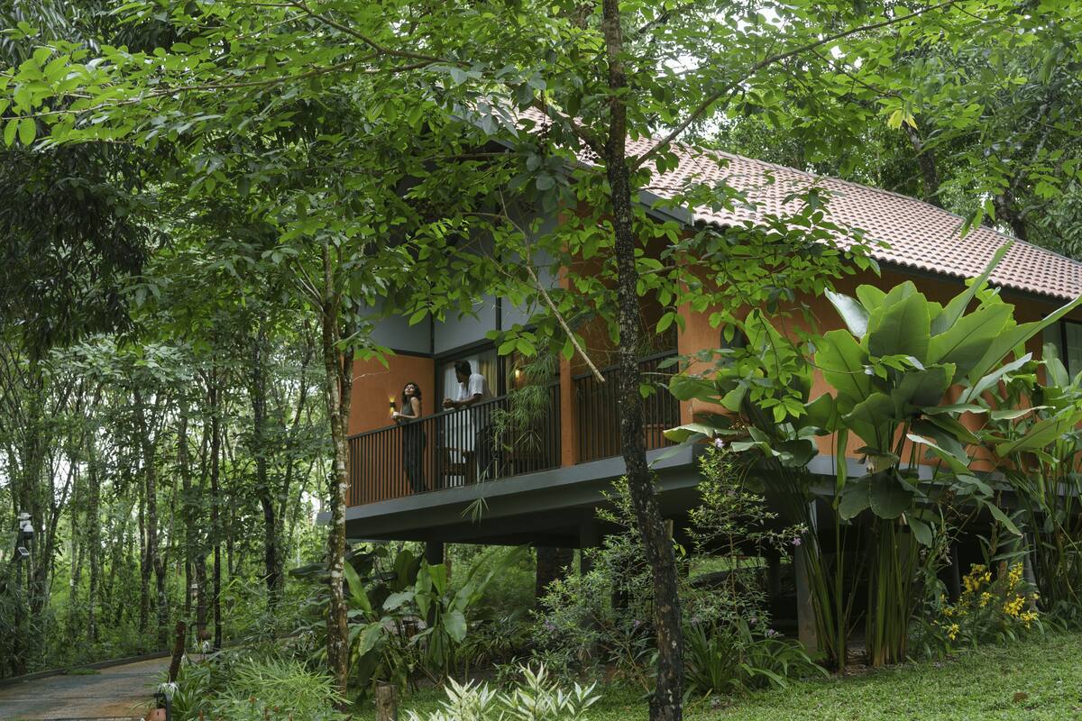 A house with a balcony overlooking a lush garden.