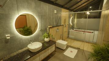 A modern bathroom with a large round mirror, a sink, a toilet, and a bathtub.