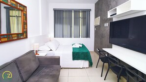 Una camera d'albergo con un letto, una scrivania, una televisione e una finestra con tende.