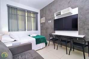 Een moderne hotelkamer met een bed, een televisie, een bureau met stoelen en een raam met blinds.