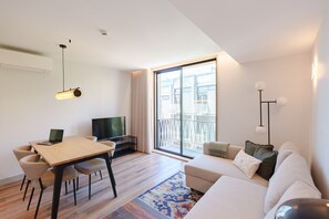 A modern living room with a sofa, a dining table with chairs, a TV, and a balcony with a railing. - Feel Porto Firmeza Coworking Flat 1 1 (Porto)