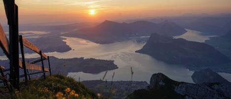 A scenic view of a mountainous landscape with a river and a sunset.