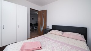 A bedroom with a bed, a bedside table, a wardrobe, and a door leading to another room. - 2 bedroom nice home in Pula (Pula)