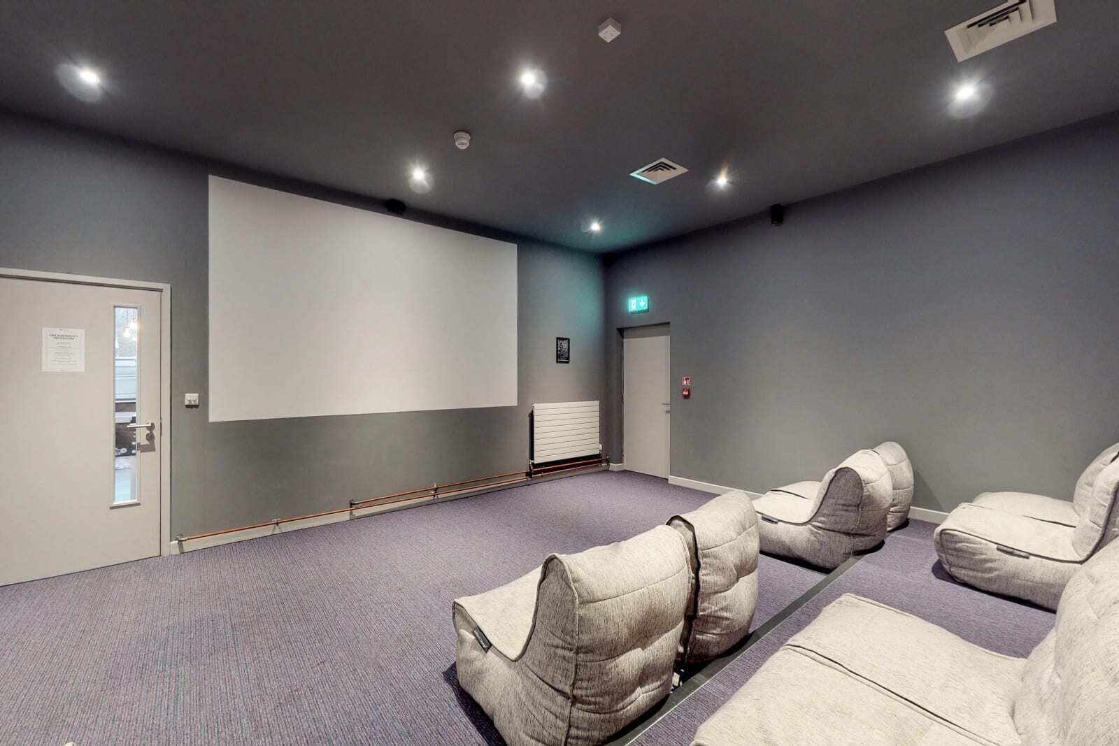 Une salle de conférence équipée d’un grand écran, d’une porte et d’un radiateur.