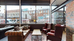 A modern lounge with leather sofas, a coffee table, and a view of the street through large windows. - For Students Only Stepney Yard in Newcastle (Newcastle-upon-Tyne)