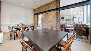 A conference room with a large table, chairs, a whiteboard, and a brick wall. - For Students Only Stepney Yard in Newcastle (Newcastle-upon-Tyne)