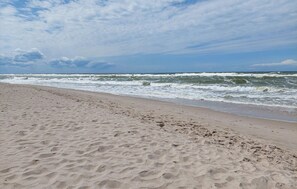 A sandy beach with footprints leading to the water, a clear sky, and waves approaching the shore. - 2 bedroom amazing home in Pogorzelica (Pogorzelica)