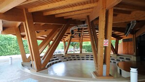 A covered outdoor area with wooden beams, a curved seating area, and a no-smoking sign. - Happy Camp in Camping Riccione (Riccione)