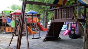 A playground with swings, slides, and a climbing structure. - Happy Camp in Camping Riccione (Riccione)