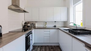 Eine kleine Küche mit weißen Schränken, einem eingebauten Backofen und einem Fenster, das für natürliches Licht sorgt.