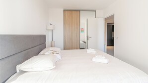 A modern hotel room with a large bed, a wooden door, and a visible bathroom.