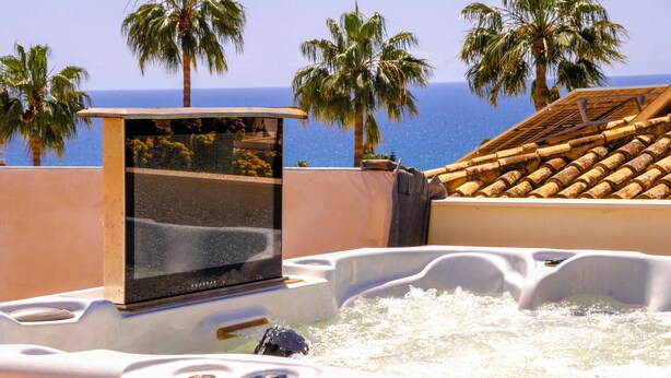 A hot tub with a television, surrounded by palm trees and a view of the ocean. - 6 bedroom villa with sea views (Mijas)