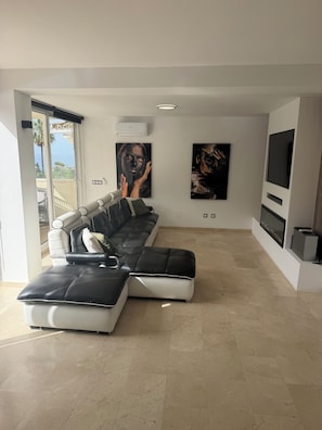 A modern living room with a sectional sofa, a flat-screen TV, and artwork on the walls. - 6 bedroom villa with sea views (Mijas)
