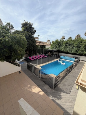 A swimming pool with a covered deck, surrounded by greenery and a tiled patio area. - 6 bedroom villa with sea views (Mijas)