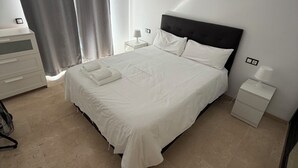 A neatly arranged bedroom with a bed, bedside tables, a dresser, and a chair.
