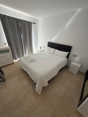 A neatly arranged bedroom with a bed, bedside tables, a dresser, and a chair. - 6 bedroom villa with sea views (Mijas)