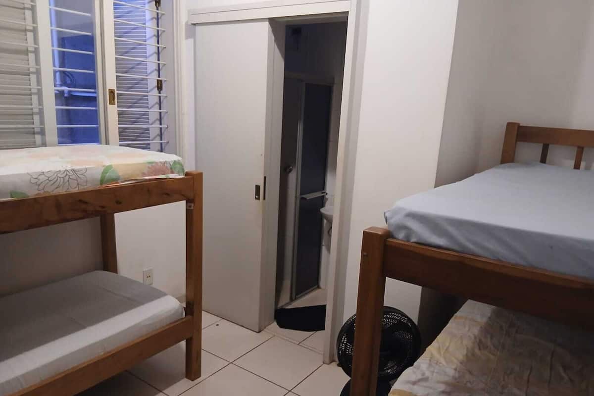 Ein Zimmer mit zwei Etagenbetten, einer Tür zu einem Badezimmer und einem Deckenventilator.