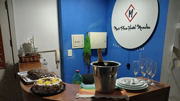A reception desk with a cake, a champagne bucket, and a plate with cutlery. - Man's Place Hostel Masculino (Porto Alegre)