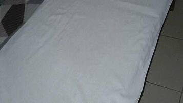 Una cama con sábana blanca y una etiqueta que dice 'HOTEL DALLAS'.