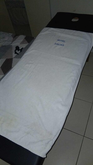 Un lit avec un drap blanc et une étiquette indiquant « HÔTEL DALLAS ».