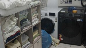 A laundry room with a washing machine, dryer, and stacked laundry. - Man's Place Hostel Masculino (Porto Alegre)