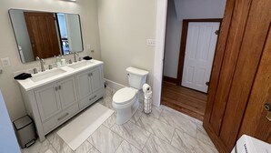 Un baño moderno con lavamanos doble, inodoro y espejo.
