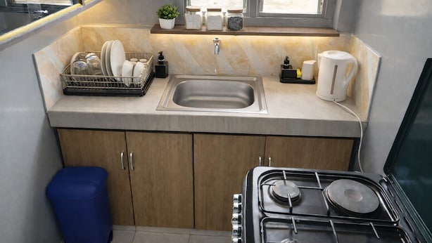 Una cocina compacta con un lavamanos, estufa y escurreplatos.