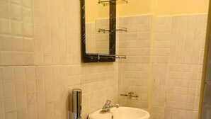 Un baño con un lavabo blanco, un espejo y paredes de azulejos.