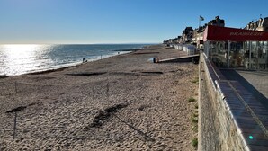 Een strand met een promenade, een restaurant genaamd 'BRASSERIE', en een heldere lucht.