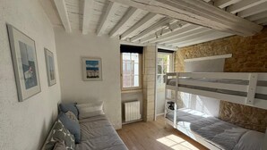 Een gezellige kamer met een stapelbed, een slaapbank en een raam.