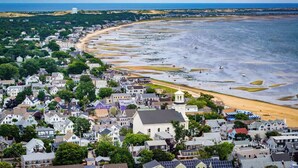 A coastal town with a sandy beach, residential buildings, and a prominent church. - Oceanfront Getaway with Deck, Steps to Provincetown Fun (Provincetown)