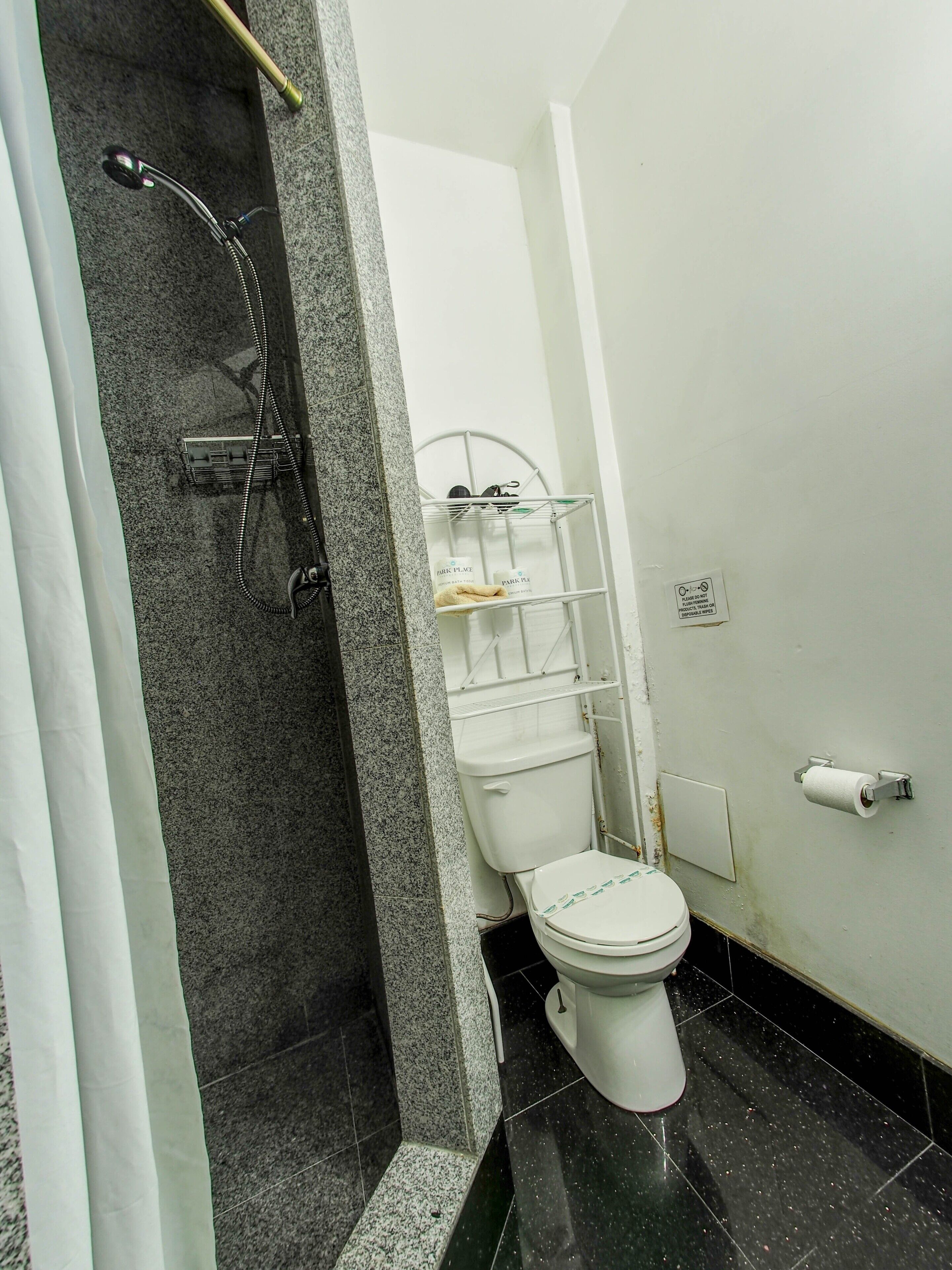 A bathroom with a shower, toilet, and a towel rack.