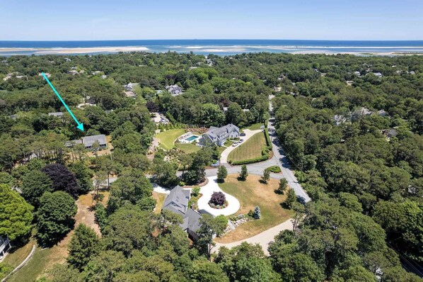 An aerial view of a residential area with a large house surrounded by dense trees, a swimming pool, and a curved driveway. - Walk to Water, near Downtown Chatham! (Chatham)