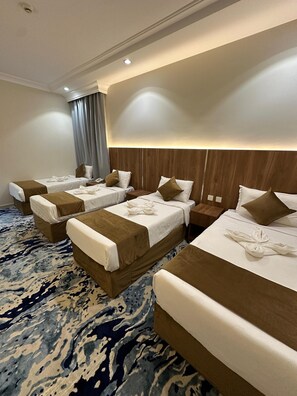 A hotel room with two beds, a wooden headboard, a patterned carpet, and a large window with curtains. - Abeer Al Azizia Hotel (Makkah)
