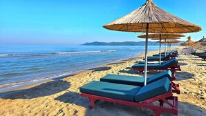 A beach with rows of sun loungers and thatched umbrellas. - Perla Modern Penthouse 217 (Gjiri Lalzit)