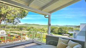 A balcony with a bed, a view of a garden, and a mountainous landscape. - Perla Modern Penthouse 217 (Gjiri Lalzit)