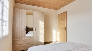 Quarto com guarda-roupa de madeira, uma cama e uma porta.