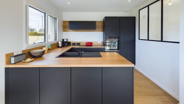 A modern kitchen with a central island, black cabinets, and a wooden countertop. - House for 10 - Garden - 600m from the beach (Penmarch)