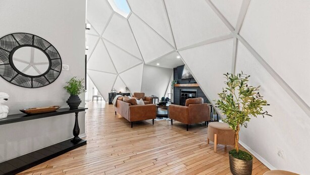 A modern living space with a geometric ceiling design, a round mirror, and a wooden floor. - Dome Manor / Pool + Hot Tub + Two Game Rooms (Bedford)