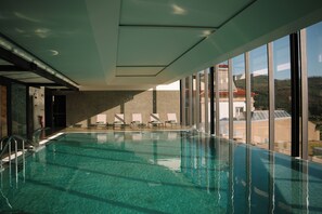 A modern indoor swimming pool with clear water, sunlit by large windows, and a view of a hilly landscape. - The Vinea Collection Hotel by Piamonte Hotels (Monção)