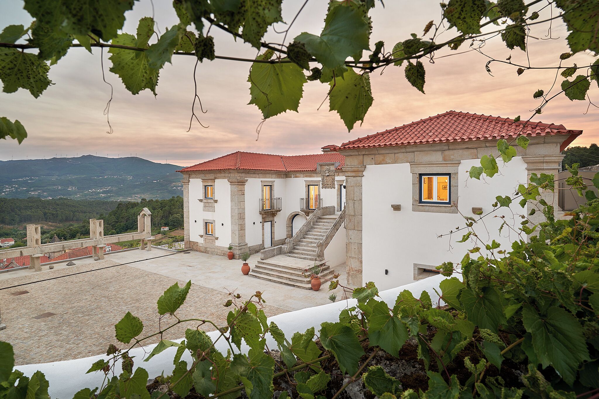 A building with a red-tiled roof, a staircase, and a view of the surrounding landscape.