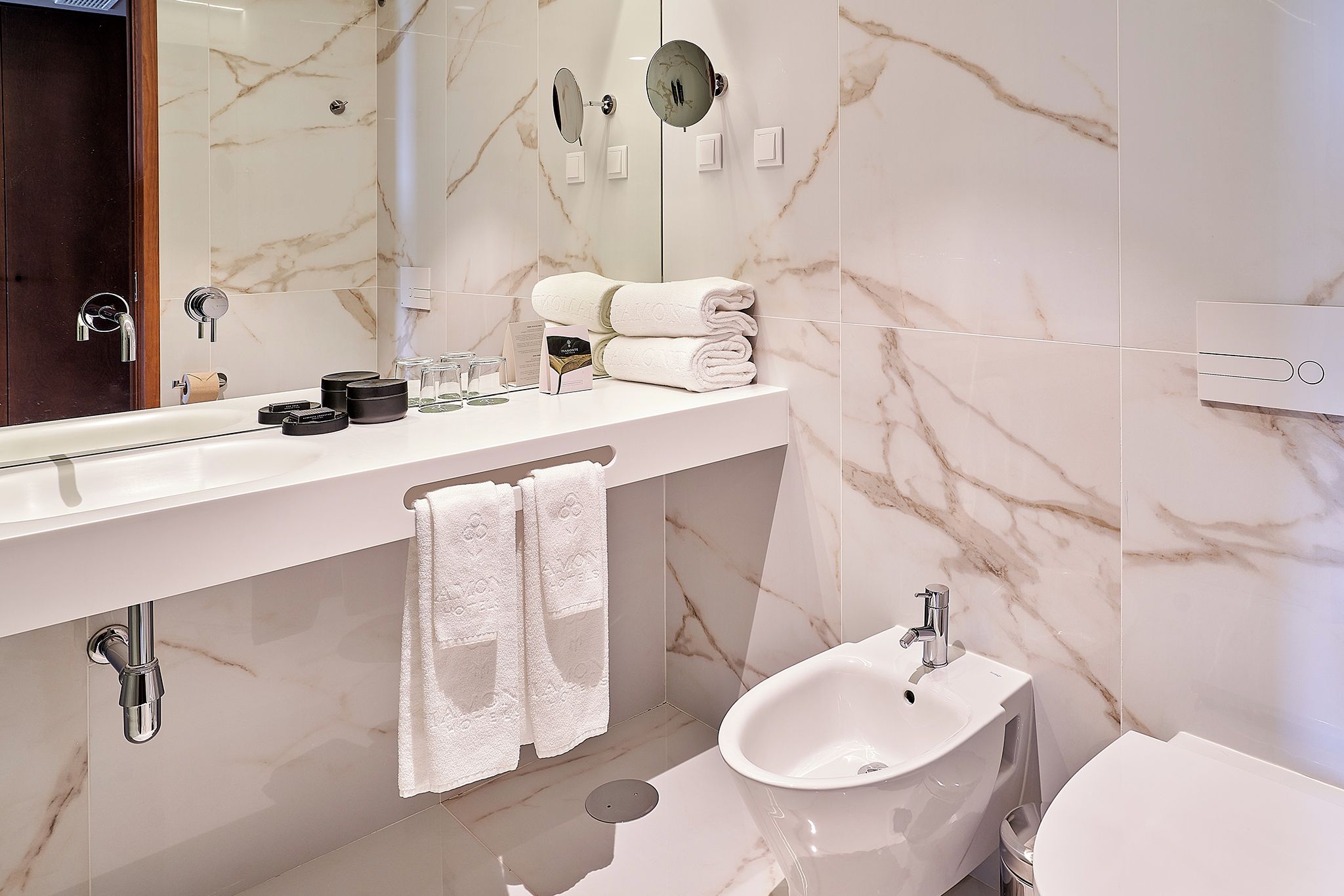 A modern bathroom with a marble vanity, a bidet, and a large mirror.