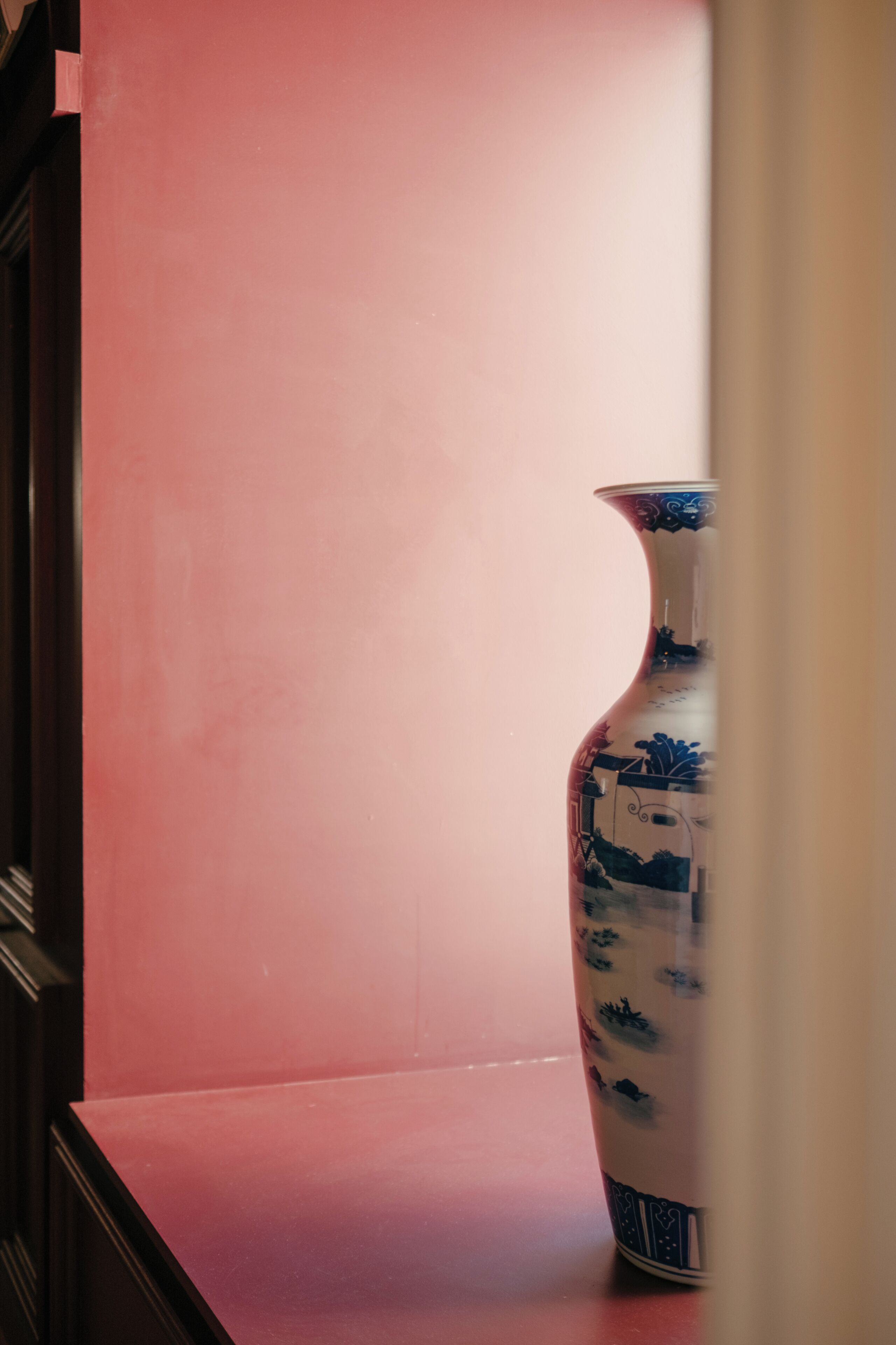 Un florero con un diseño tradicional sobre una mesa frente a una pared lisa.