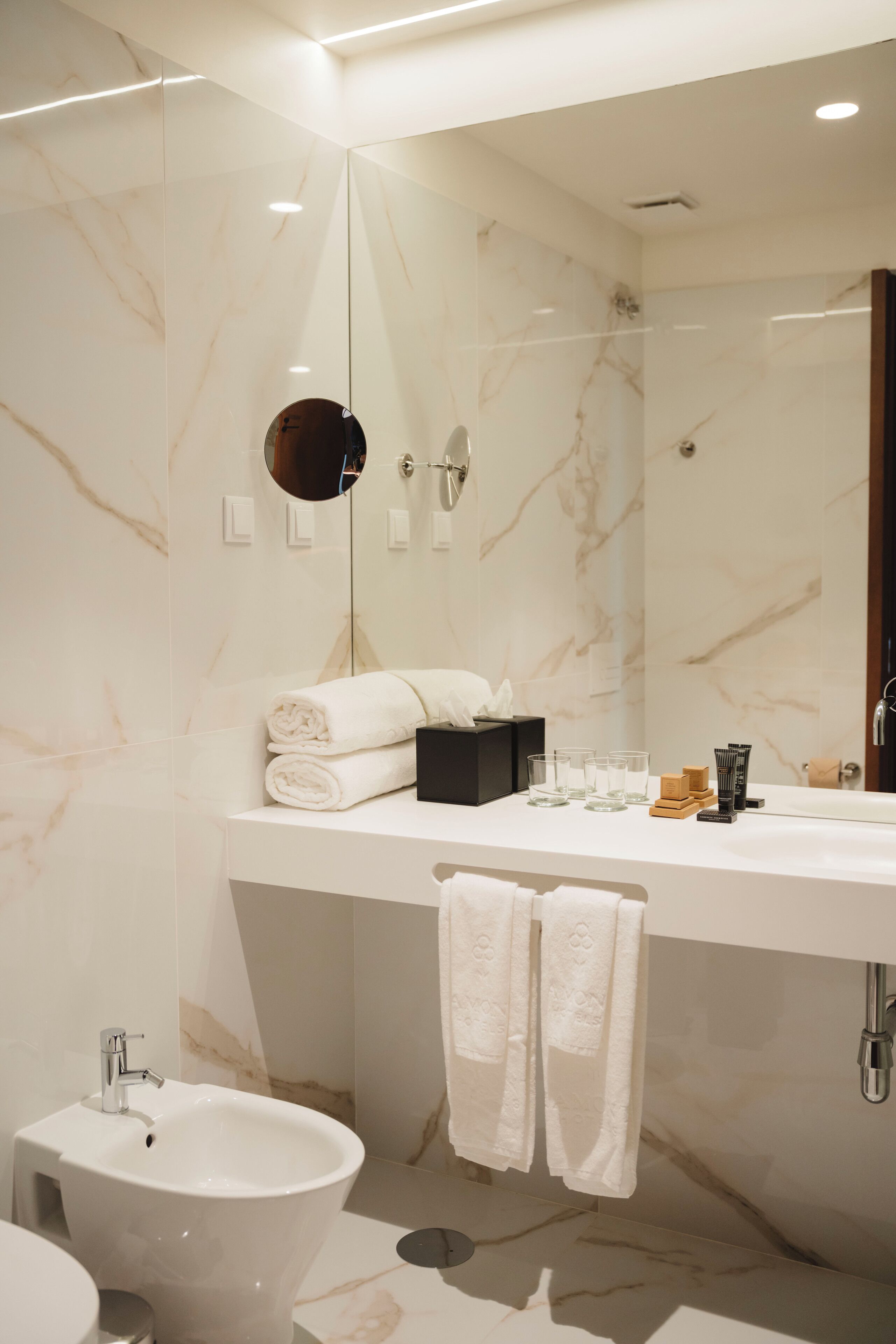 Une salle de bain moderne avec un meuble-lavabo en marbre, un lavabo, un bidet et un miroir.