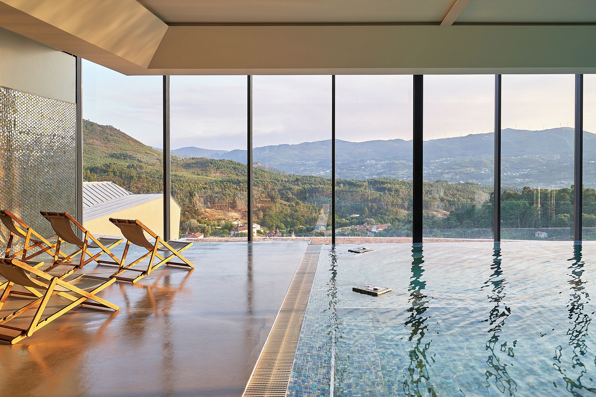 Una piscina techada, sombrillas, sillones reclinables de piscina