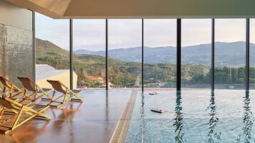 Una piscina techada, sombrillas, sillones reclinables de piscina